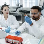 Dois cientistas analisam amostras e registram dados em um laboratório.