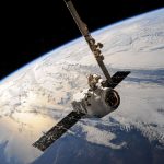 Satélite em órbita sobre a Terra, com nuvens visíveis contra o fundo do espaço.