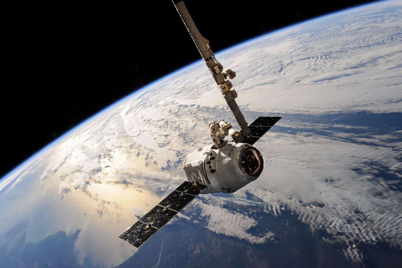 Satélite em órbita sobre a Terra, com nuvens visíveis contra o fundo do espaço.