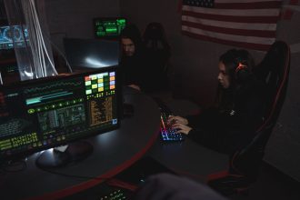 Profissionais analisam sistemas de computador em uma sala pouco iluminada, acompanhando dados relacionados à segurança cibernética.
